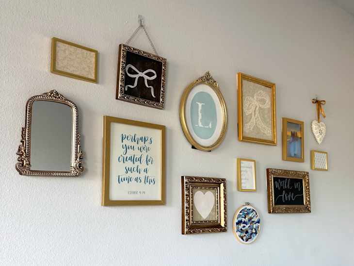 Gallery wall featuring various framed art pieces, mirrors, and decorative elements in gold and neutral tones.