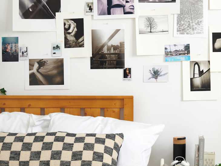 close shot of bed with checkered black and cream pillows and photos on the wall
