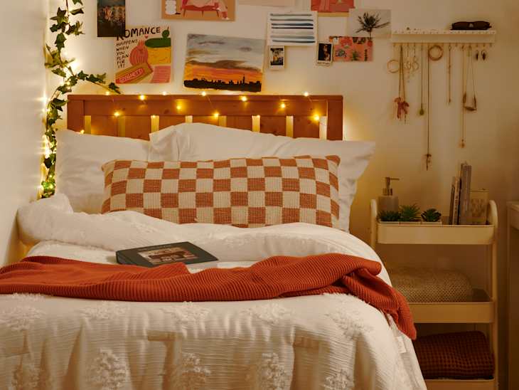 forward shot of bedroom with lights wrapped around the headboard and vine lights on the wall with photos on the wall