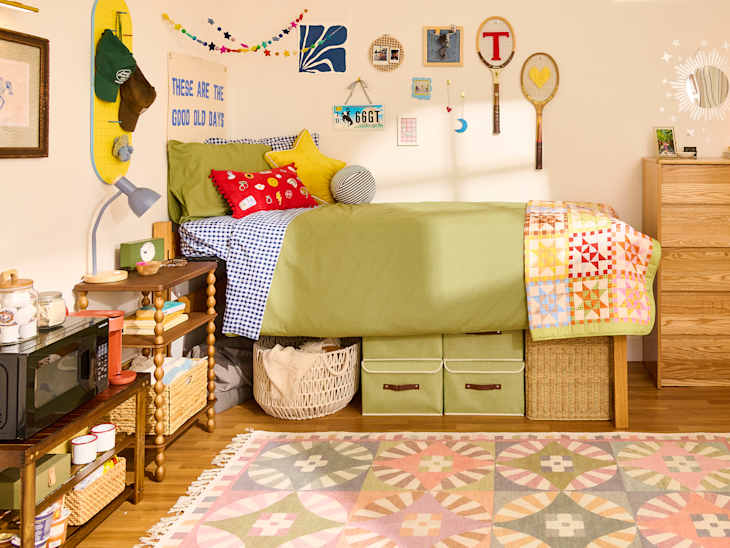 Cozy bedroom with a green bedspread, colorful quilt, checkered pillows, and decorative wall art.