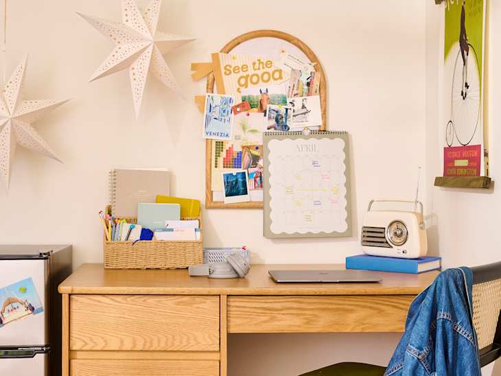 A wooden desk with a laptop, a calendar, and a vintage radio, surrounded by decorative stars and a bulletin board.