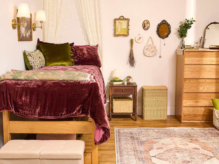Cozy bedroom with a lofted bed, burgundy bedding, decorative pillows, wooden dresser, and wall art.