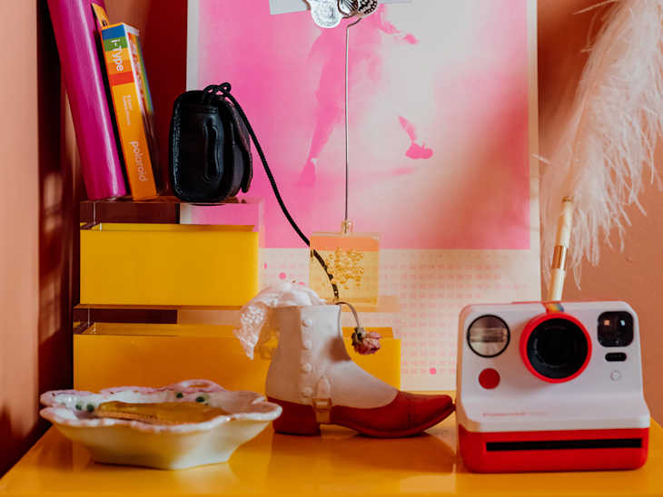 Vintage polaroid on colorful night stand topped with other decorative items.