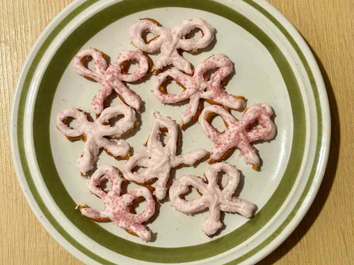 Chocolate pretzel bows with pink dye and sugar.