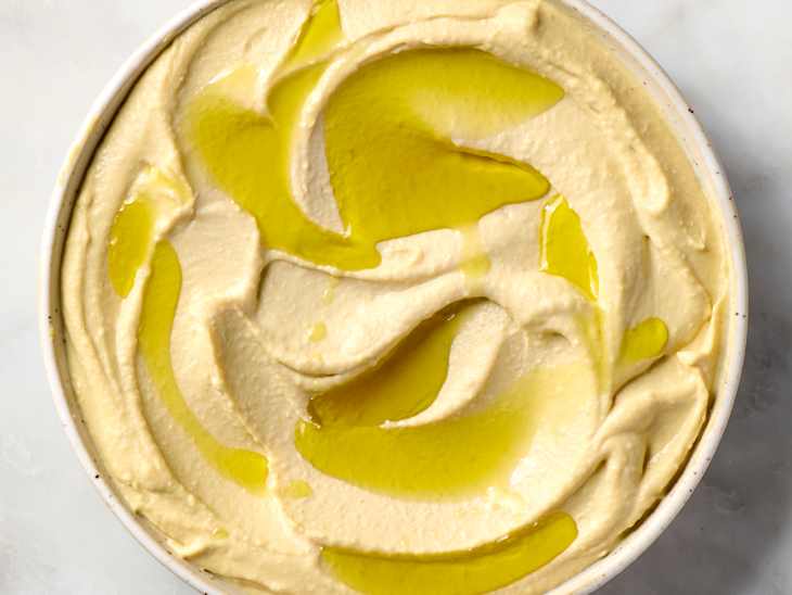 overhead shot of a bowl of hummus, topped with olive oil