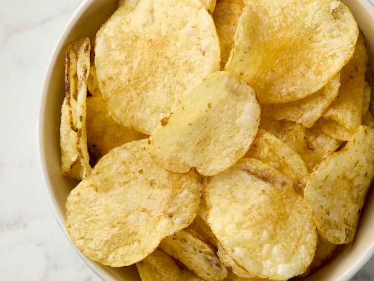 overhead shot of potato chips in a beige bowl