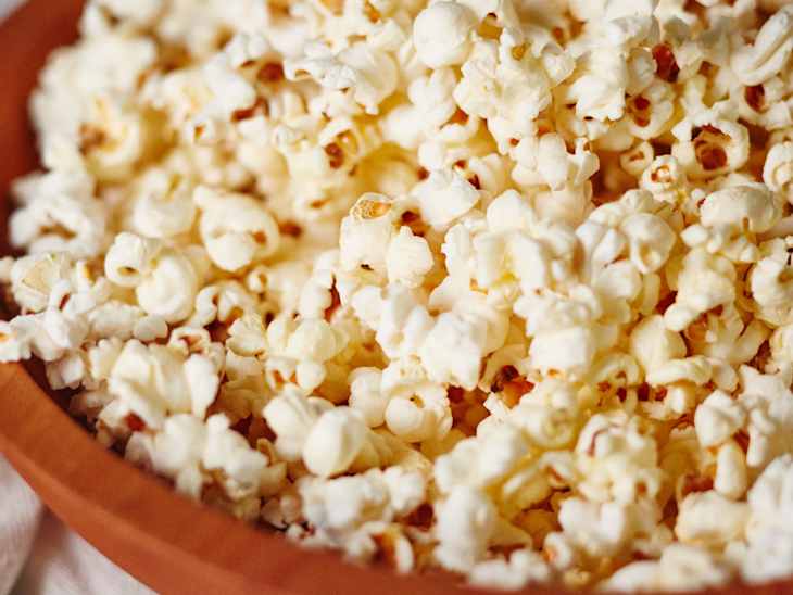 Popcorn in a wooden bowl, close-up view showing fluffy kernels.