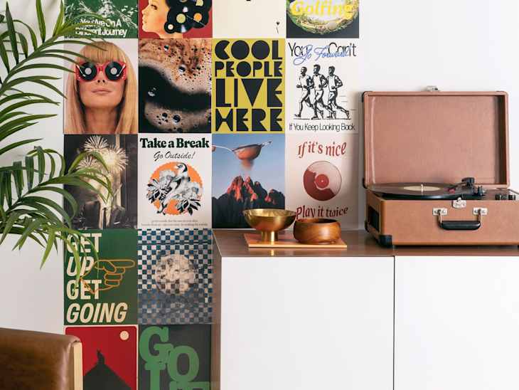 Colorful wall collage of vintage posters, a record player, and decorative bowls on a wooden surface.