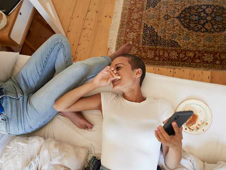 Cheerful woman looking at friend sitting on bed