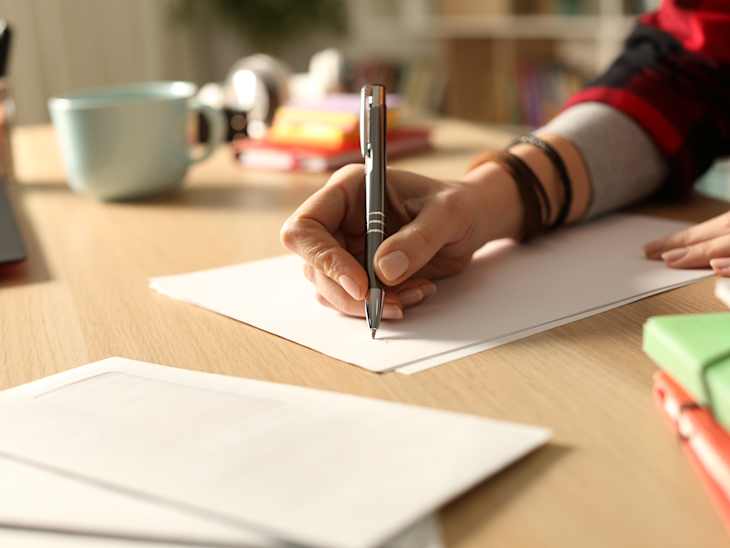 Student hand writing letter at home in the night