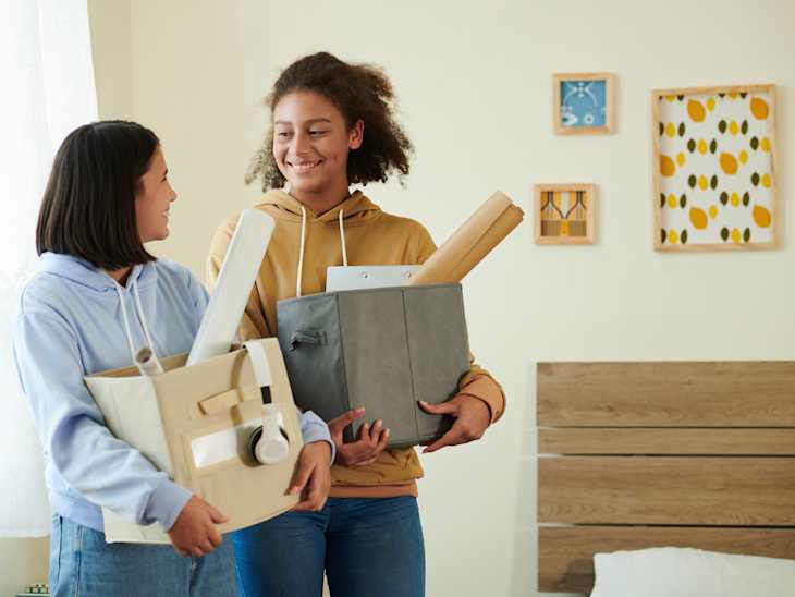 Smiling roommates with boxes of belongings meeting each other for the first time
