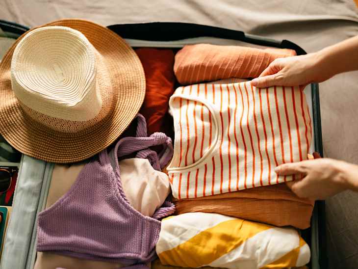 Woman Packing a Shirt in a Suitcase for a Summer Vacation