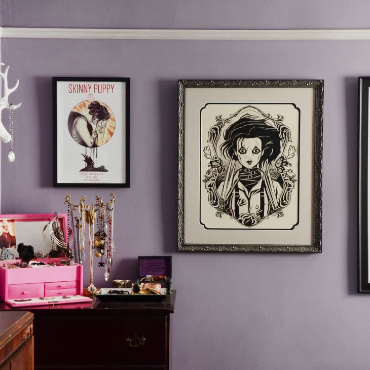 Purple room with framed art, jewelry box, and wall-mounted antlers displaying necklaces.