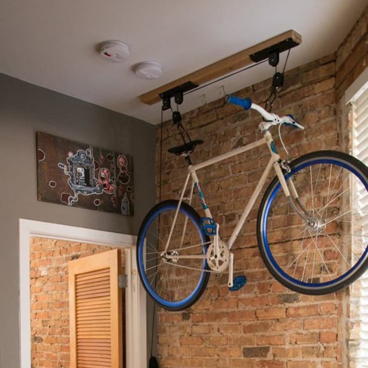 Commuter bike hanging from the ceiling in an apartment with exposed brick wall