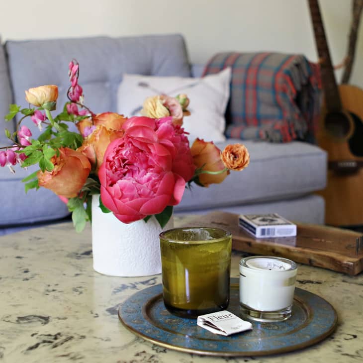 Marble coffee table with candles, flowers, and a deck of cards in front of a gray sofa and guitars.