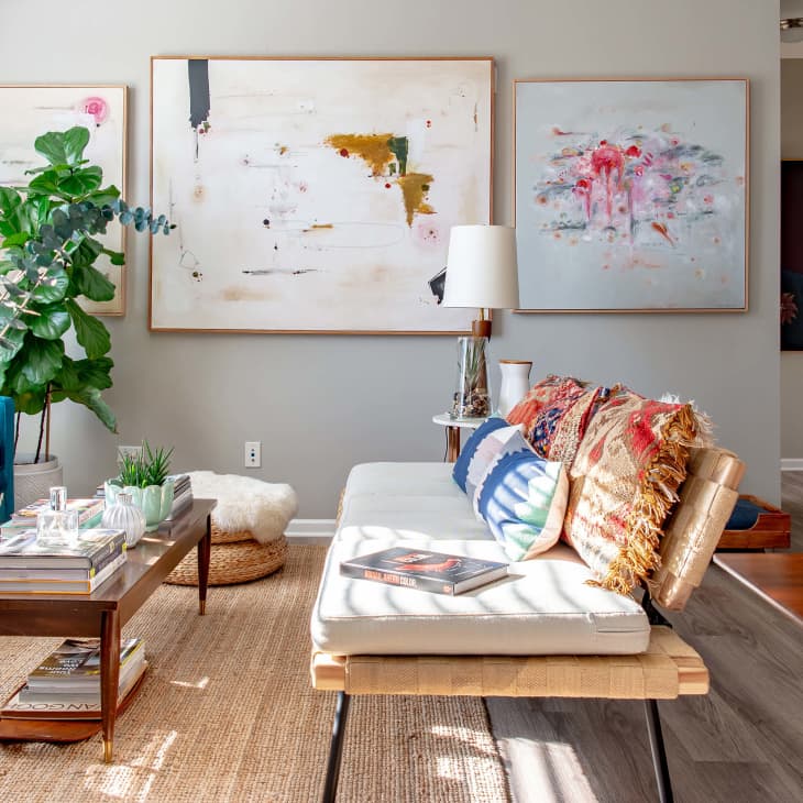 Modern living room with abstract art, blue sofa, wooden coffee table, and plants.