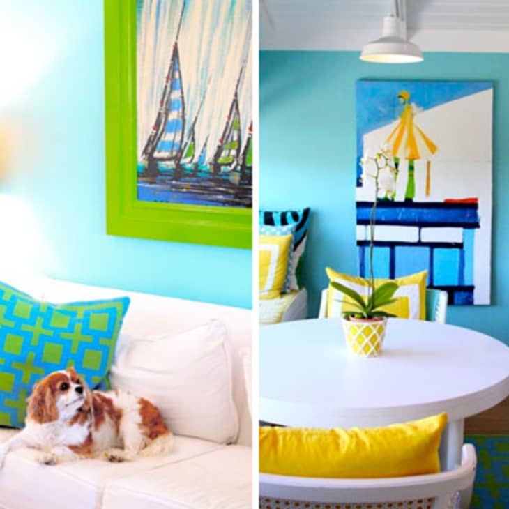 Living room with a dog on a white sofa, blue and green pillows, yellow lamp, and vibrant sailboat artwork.