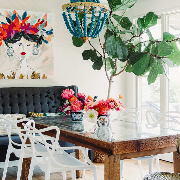 A colorful dining table with flowers and a portrait of a woman above the booth.
