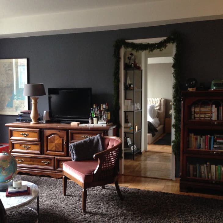 Living room with dark walls, wooden furniture, TV, globe, bookshelves, and a doorway to a bedroom.
