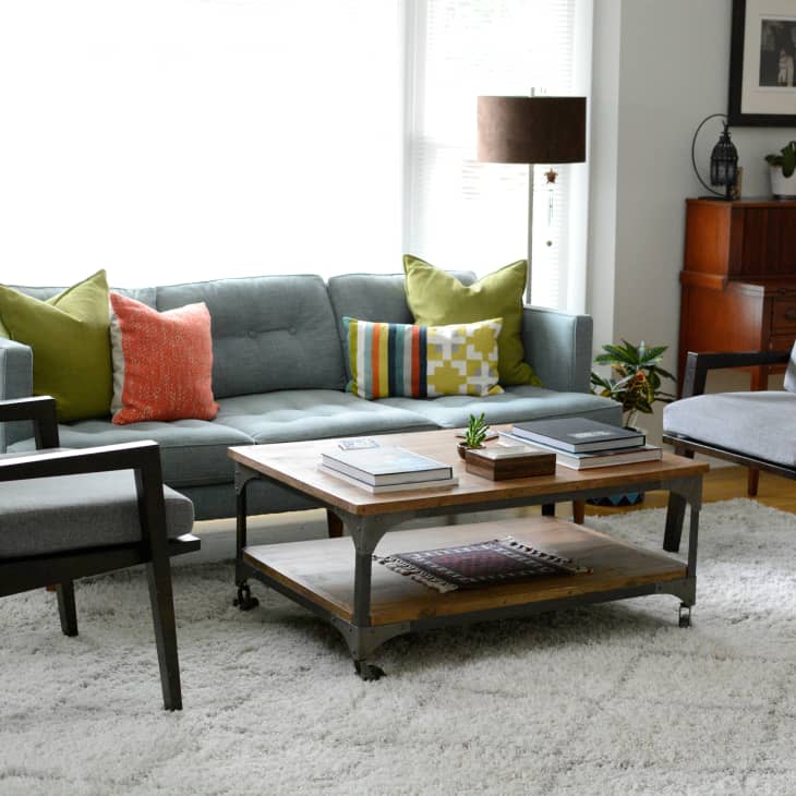 Mid-century modern living room with a gray sofa, colorful pillows, two armchairs, wooden coffee table, and a floor lamp.