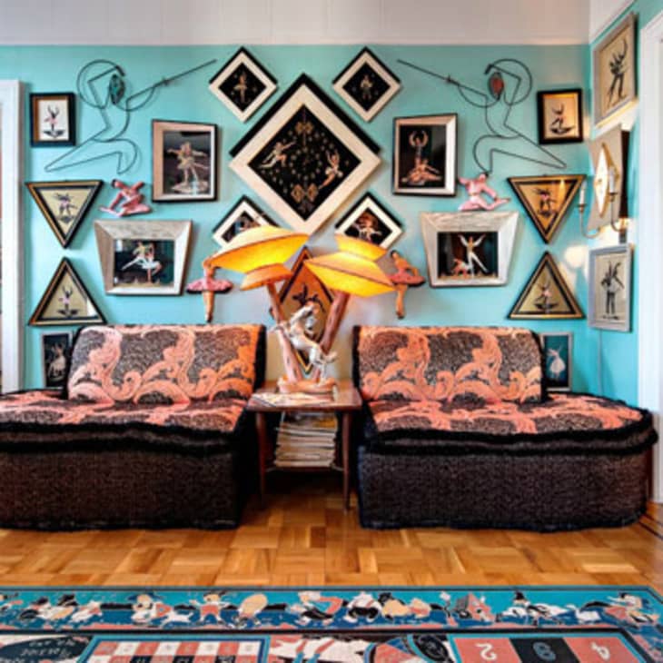 Eclectic living room with patterned sofas, vibrant wall art, and unique lamps on a wooden floor.