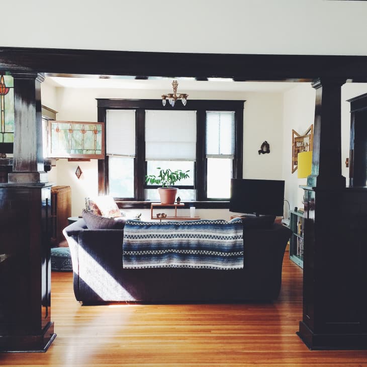 Living room with dark wood trim, stained glass windows, a patterned throw on the sofa, and a potted plant on the table.