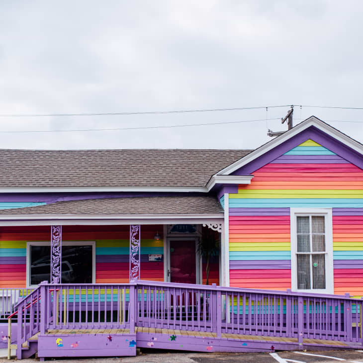 Colorful house with rainbow-striped siding and a purple ramp in front.