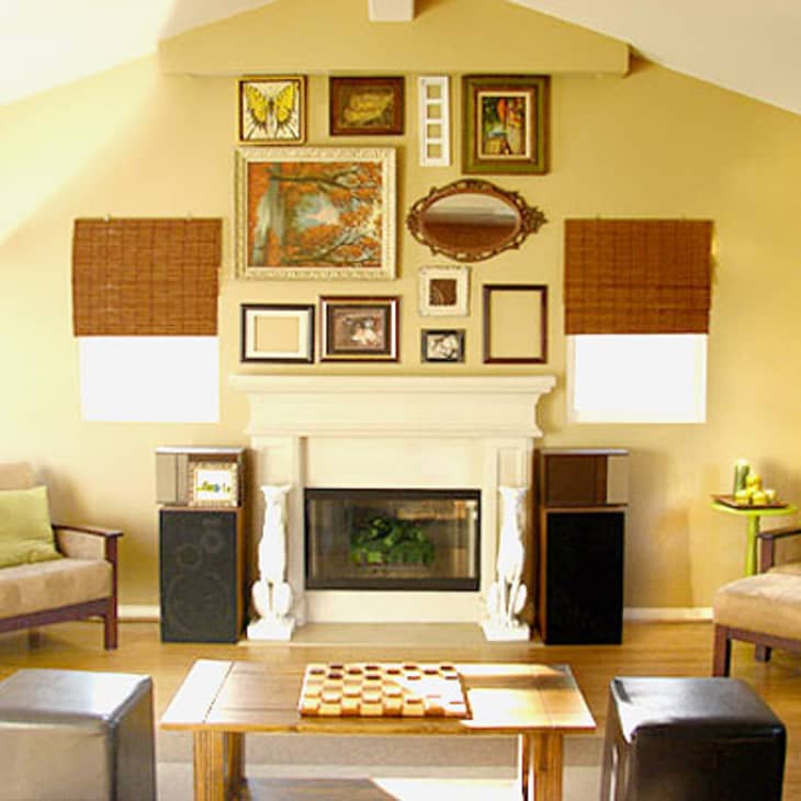 Living room with a fireplace, gallery wall, beige sofas, green cushions, and a chessboard on a wooden coffee table.