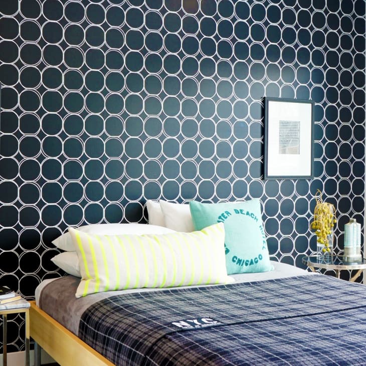 A bed with plaid bedspread and blue circle wallpaper