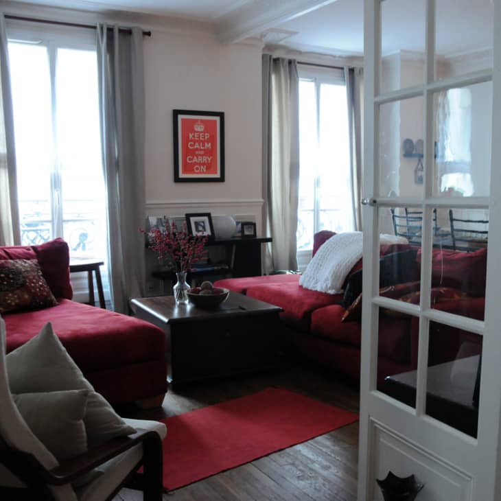 Living room with red sofas, decorative pillows, a coffee table, and a "Keep Calm and Carry On" poster on the wall.