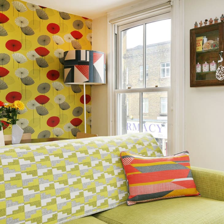 a bright green couch and abstract green patterned wallpaper
