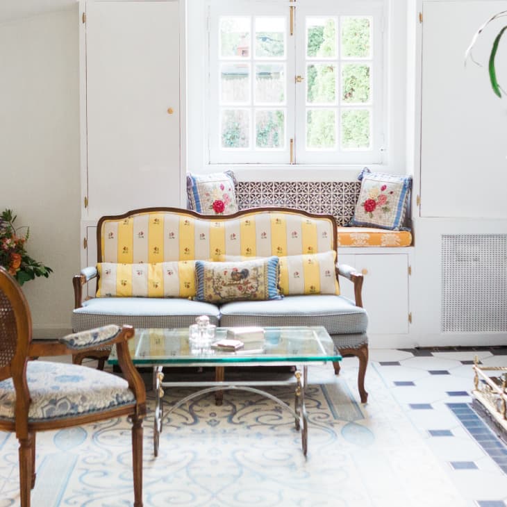 Elegant living room with vintage sofa, glass coffee table, patterned cushions, and a fireplace.