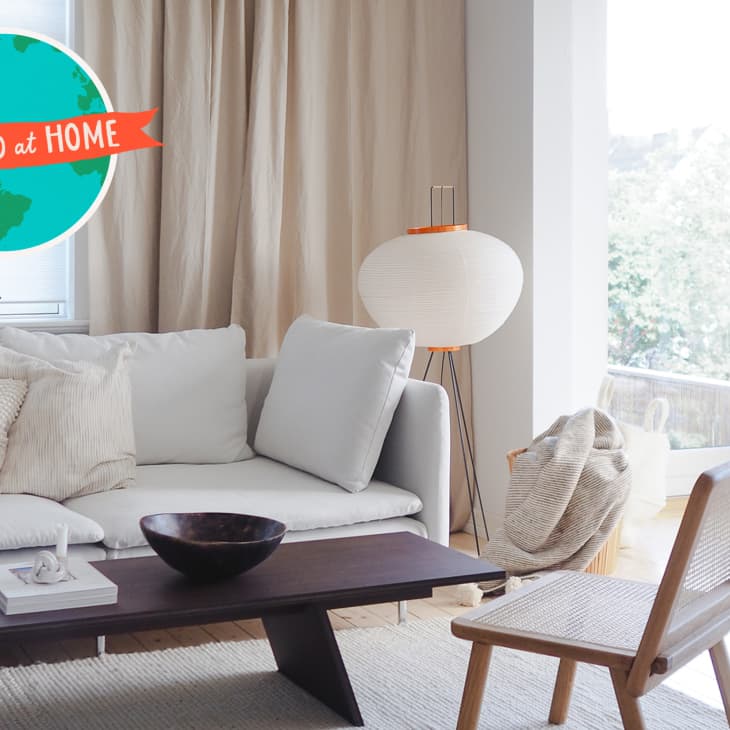 Modern living room with white sofa, wooden coffee table, and a large floor lamp near a window with beige curtains.