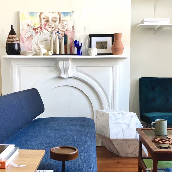 Living room with blue sofas, white fireplace, abstract art, and decorative vases on the mantel.