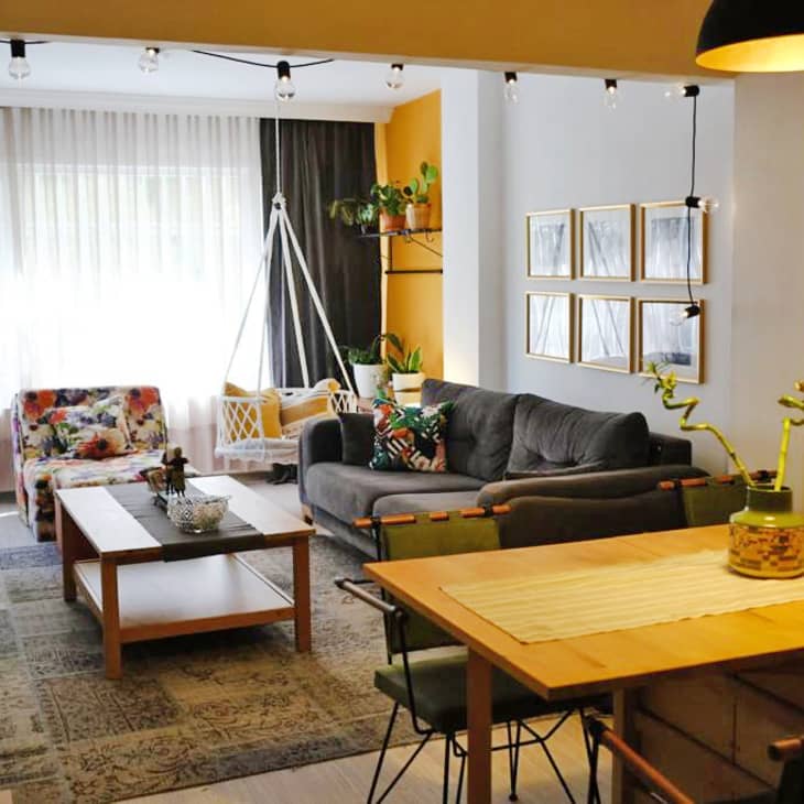 Living room with gray sofa, floral armchair, wooden coffee table, hanging chair, and framed wall art.