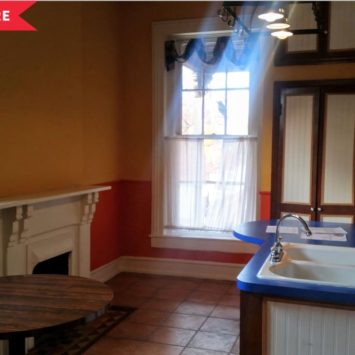 Kitchen with blue countertop, white sink, orange walls, and a fireplace.