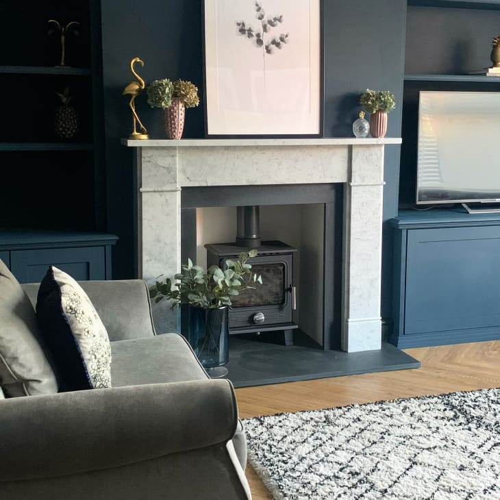 Living room with gray sofa, blue built-in shelves, marble fireplace, and a TV on a blue cabinet.