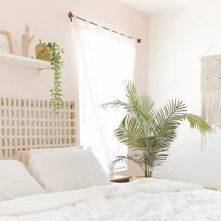 a bedroom with a pale pink accent wall