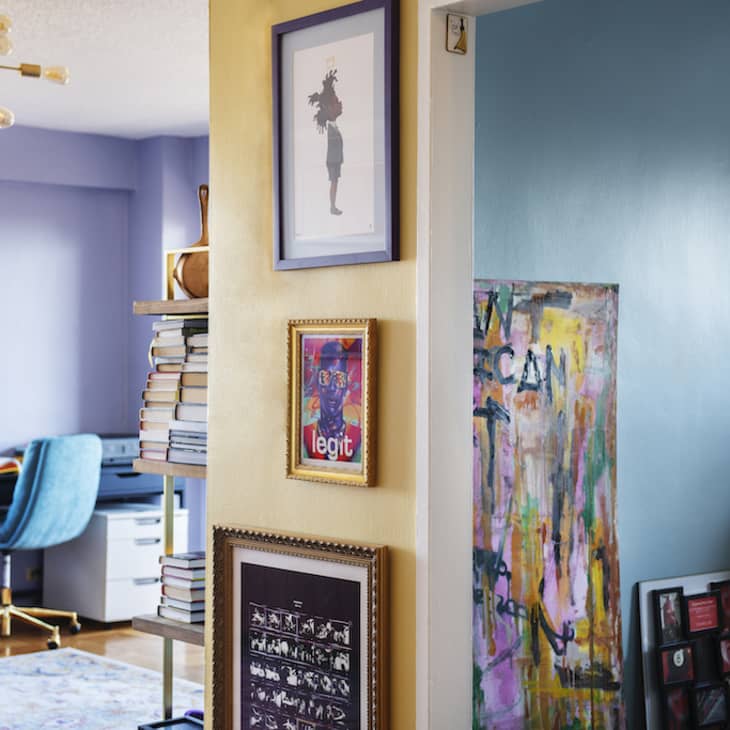 Eclectic home office with blue walls, a velvet chair, abstract art, and a modern chandelier.