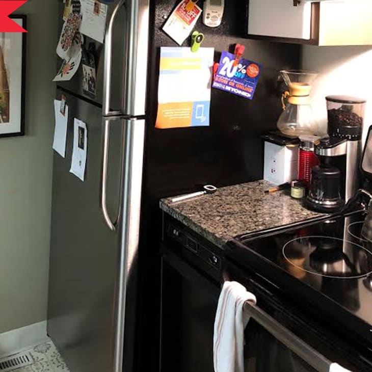 Small kitchen with stainless steel fridge, granite countertop, coffee maker, kettle, and stove.