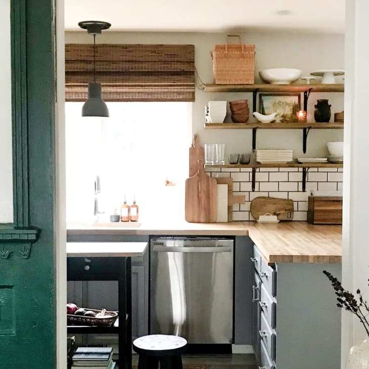 Cozy kitchen with open shelves, wooden countertops, cutting boards, and a pendant light over the sink.