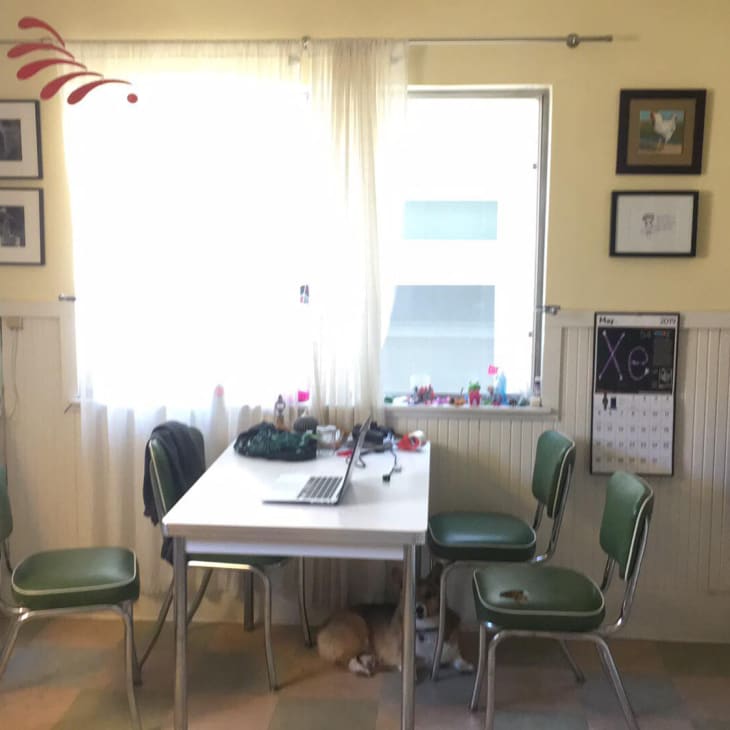 Small kitchen with vintage green chairs, white table, laptop, and wall art. Fridge covered in magnets.