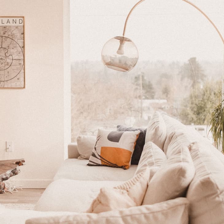 Cozy living room with a cream sofa, geometric pillows, a wooden coffee table, and a Portland map on the wall.