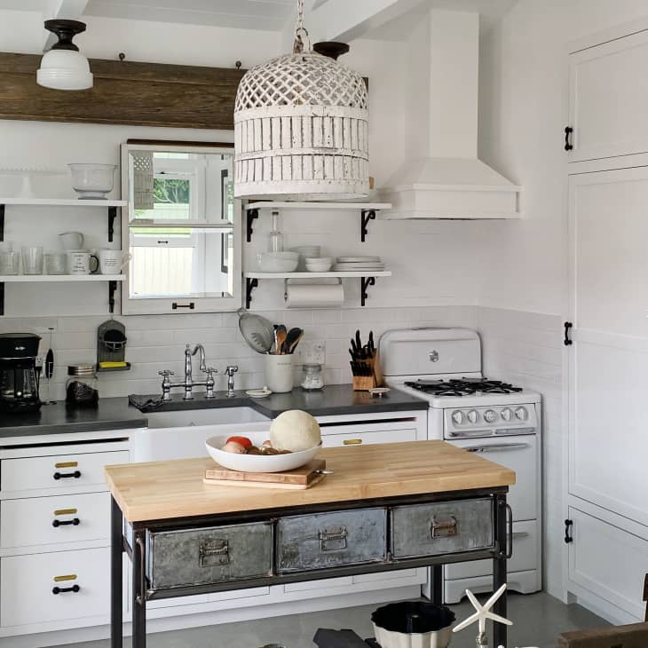Cozy kitchen with vintage fridge, open shelves, farmhouse sink, and rustic island. Sign reads "I am broke, I am bored, be quarantined."