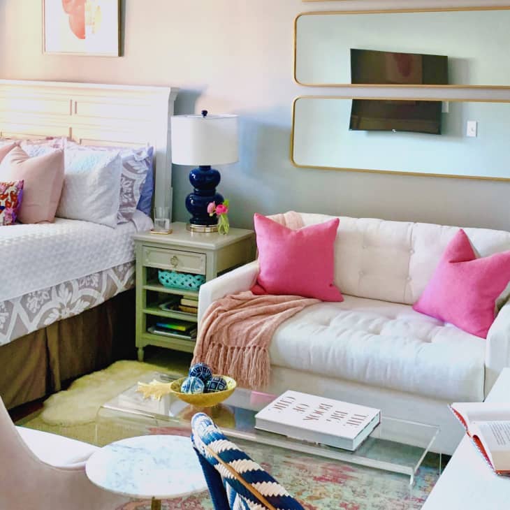 Bedroom with a white bed, pink pillows, a white sofa, and a blue lamp on a side table.