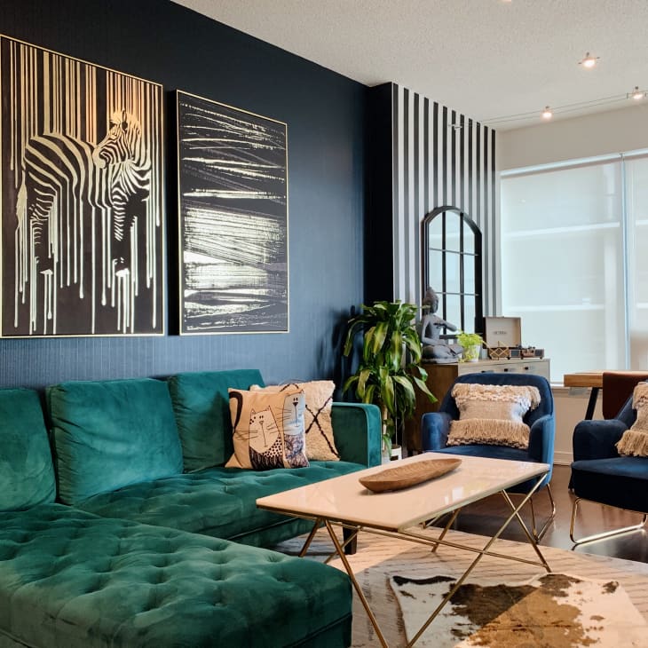 Black and white zebra art paintings on top of a dark black wall above an emerald green sectional sofa
