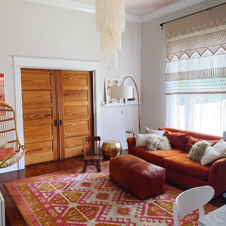 Living room with red sofa, red ottomans, red bohemian rug, and a wicker hanging chair