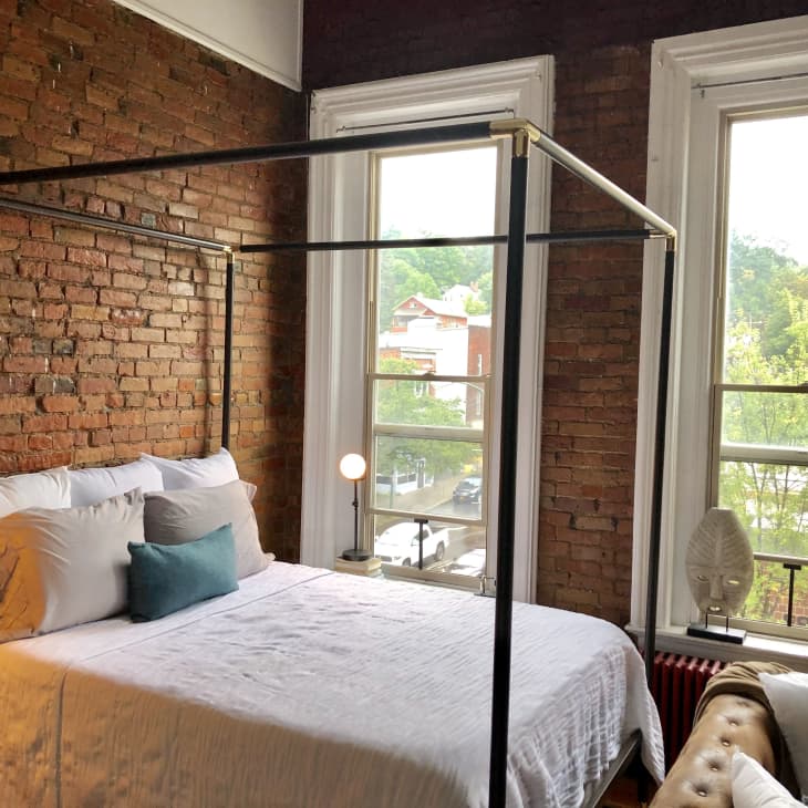 Sleeping area with sleek black metal bed frame and exposed brick walls