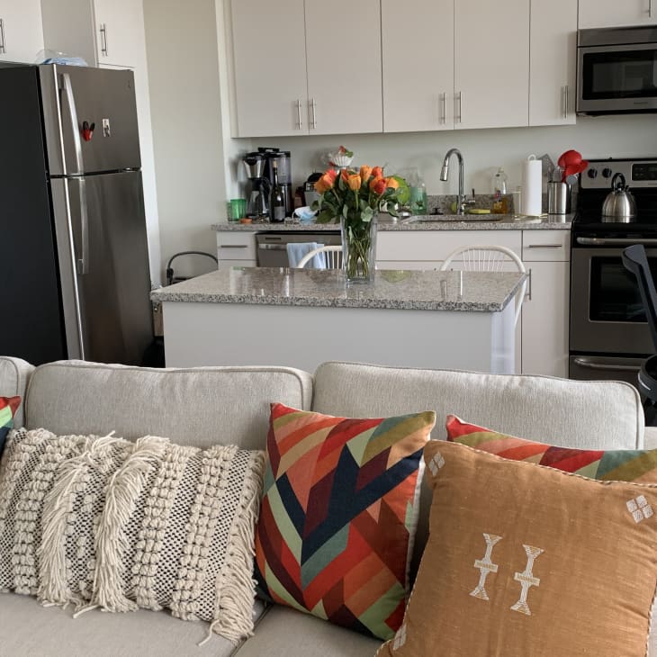 Boho and colorful pillows on couch. Kitchen in background.