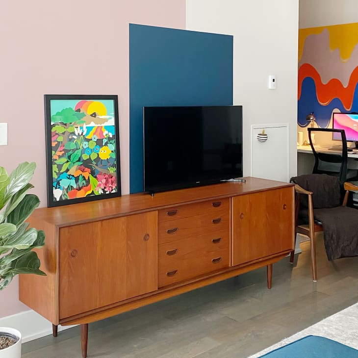 TV on mid-century credenza in front of wall with colorful painted boxes